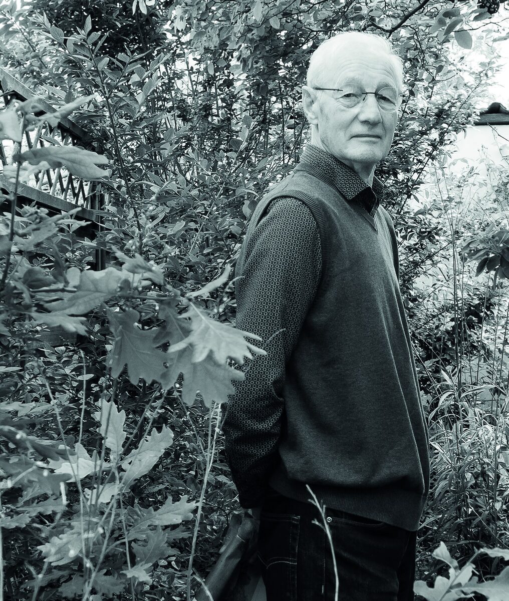 Bert van Schagen in zijn woonkamer in de Leidsebuurt, bij de grote boekenkast