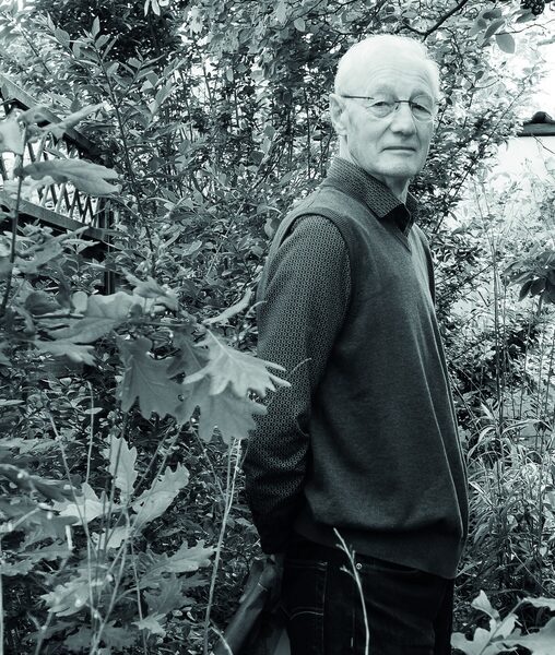 Bert van Schagen in zijn woonkamer in de Leidsebuurt, bij de grote boekenkast