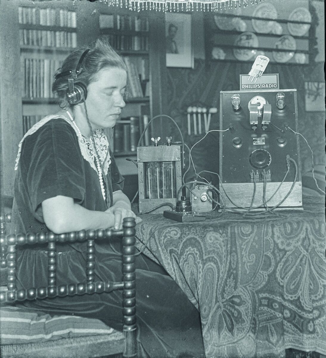 Cornelia Alphenaar luistert met gesloten ogen en hoofdtelefoon naar de radio, circa 1925-1930.