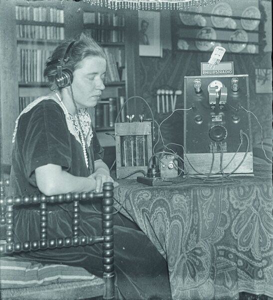 Cornelia Alphenaar luistert met gesloten ogen en hoofdtelefoon naar de radio, circa 1925-1930.