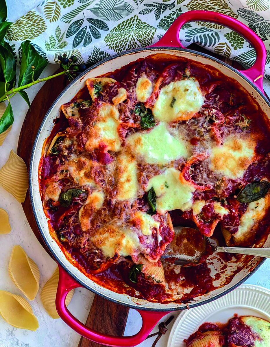 Ovenschaal met gevulde pastaschelpen in tomatensaus naast een zomerse tiramisu met perzik en aardbei